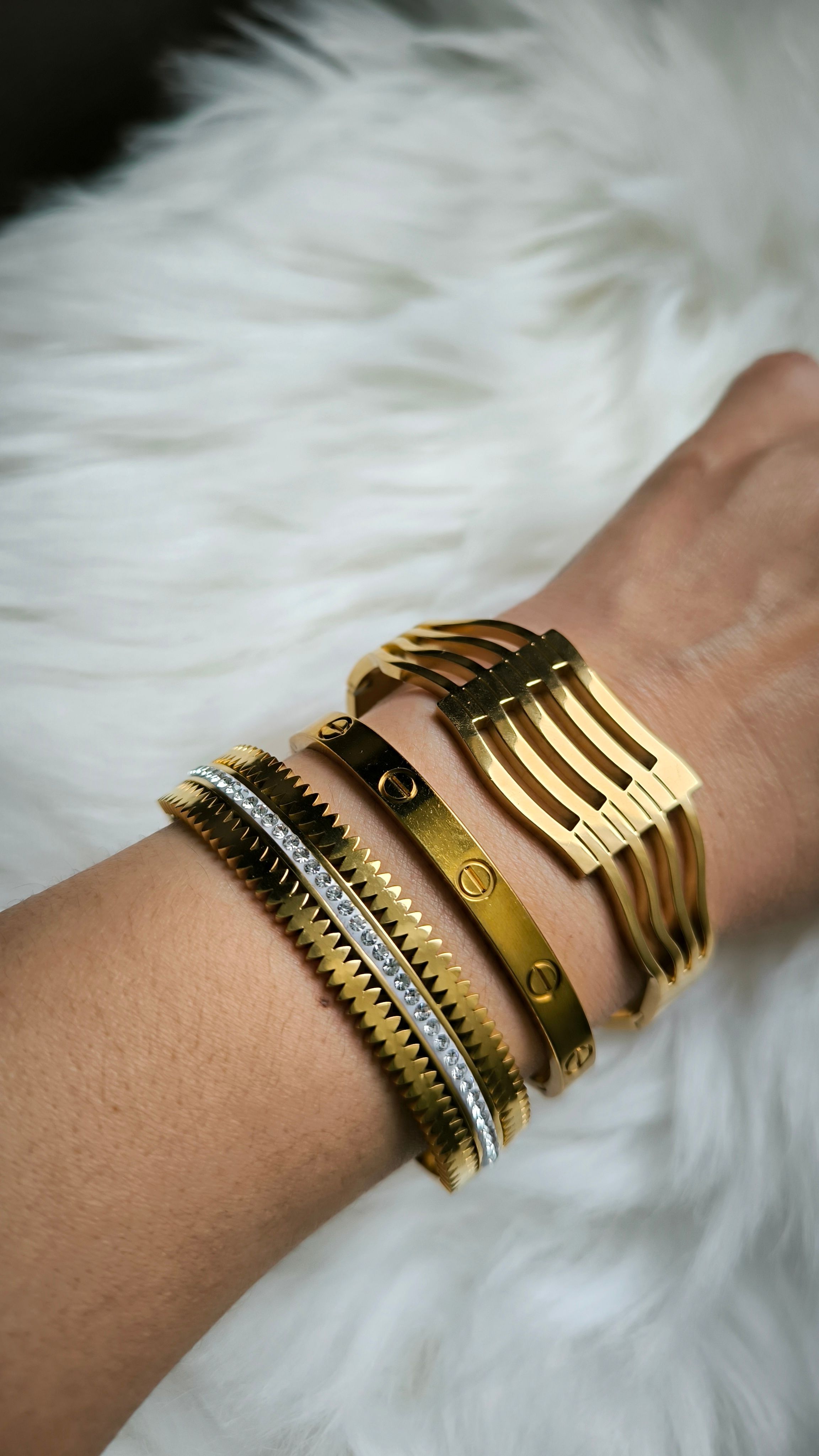Elegantes pulseiras de ouro e prata exibidas em um close no braço de uma mulher, enfatizando os detalhes da joia.