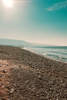 明媚的阳光下，宁静的鹅卵石海滩上，海浪轻轻拍打着海岸