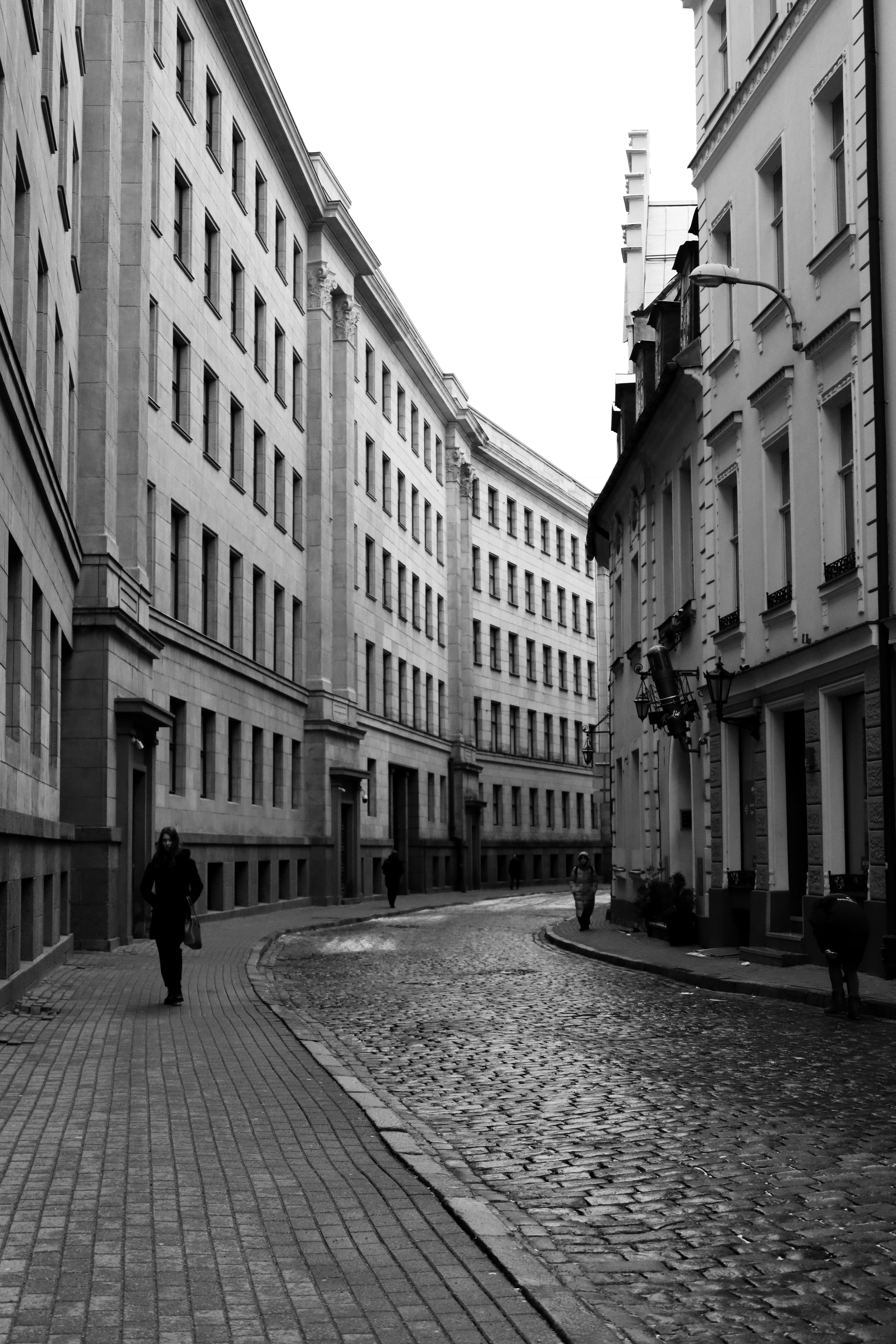 A narrow cobblestone street in Riga's old town, captured in monochrome.