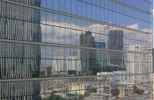 A city skyline is reflected in the glass of a building