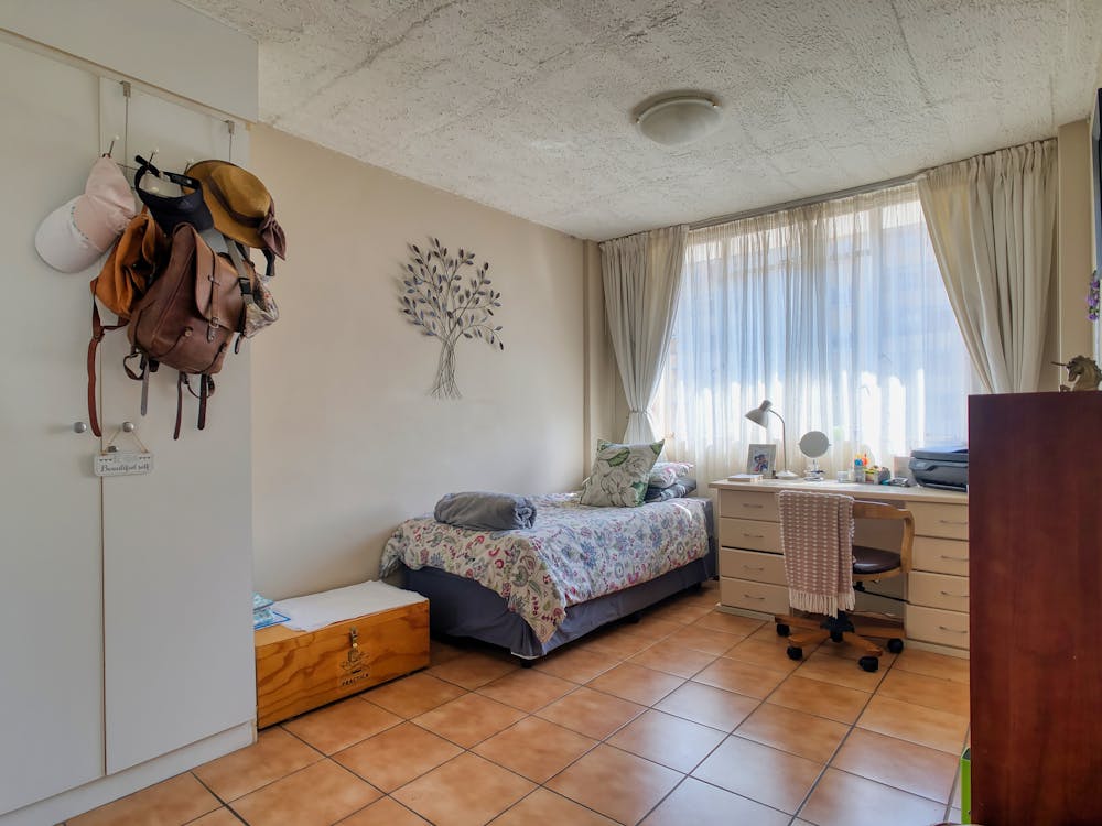 A bedroom with a bed, desk, and a window