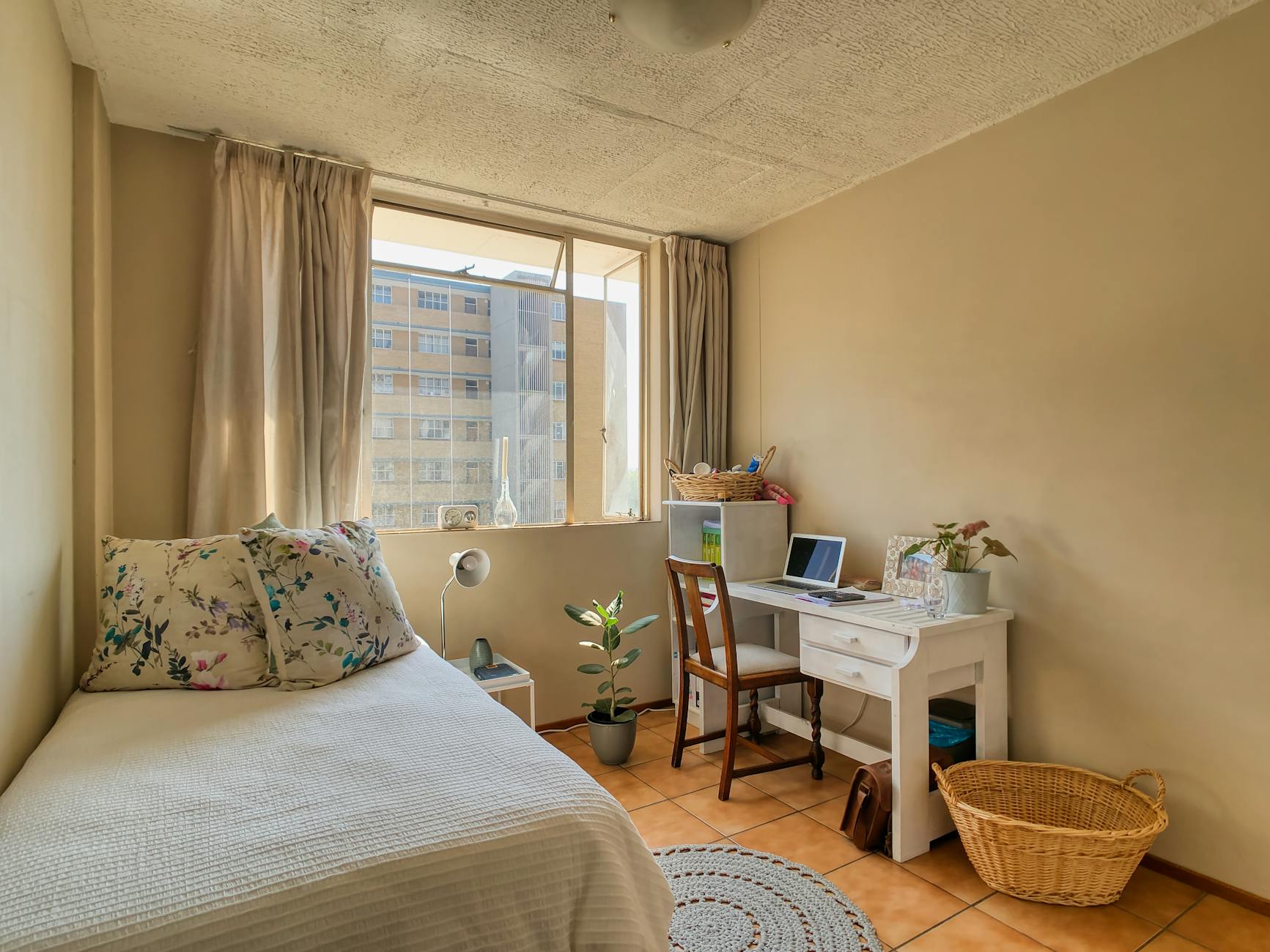 A bedroom with a bed, desk and window