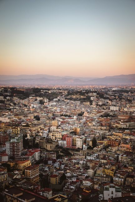 Stunning aerial cityscape of Naples, Italy during sunset with a warm, inviting glow.