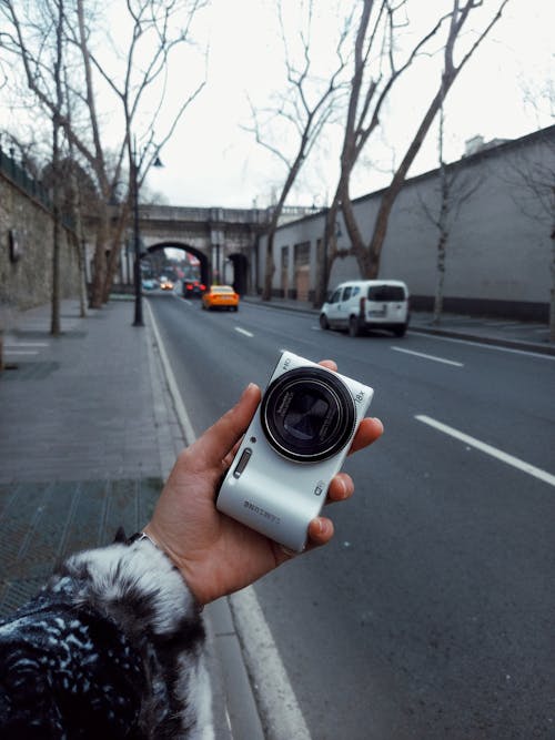 A person holding a camera on a street