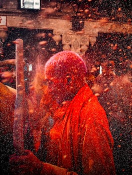 Capture of an Indian man covered in red powder during Holi festival in Barsana street.