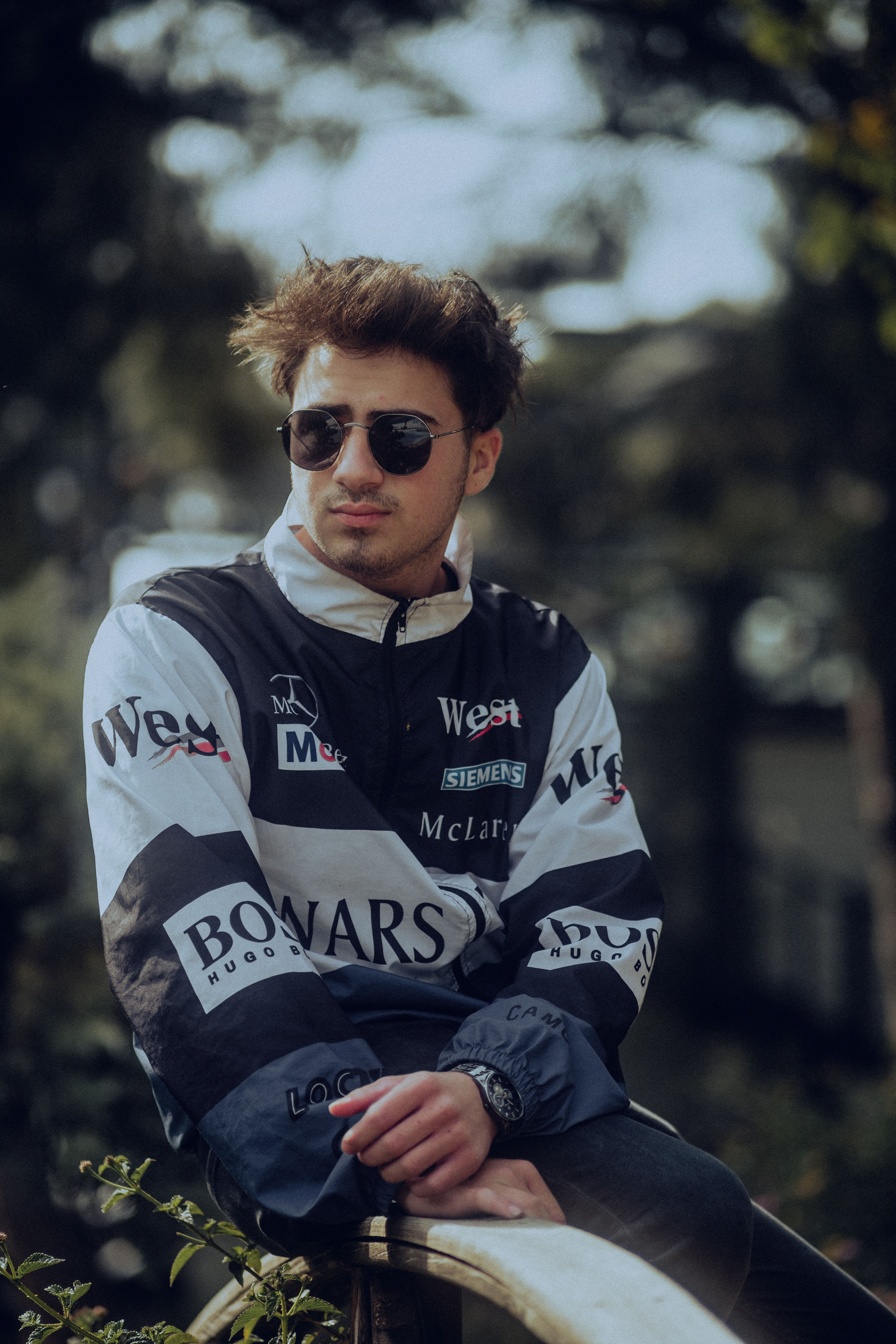 A young man wearing sunglasses sitting on a bench · Free Stock Photo