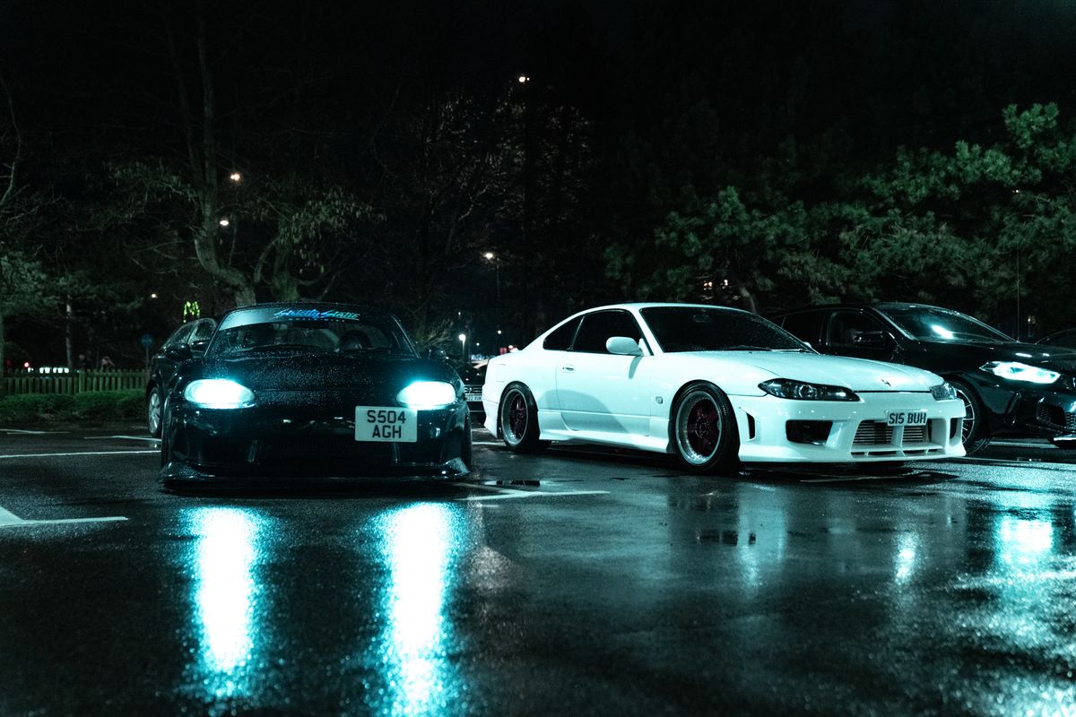 Japanese sports cars in rainy night parking lot