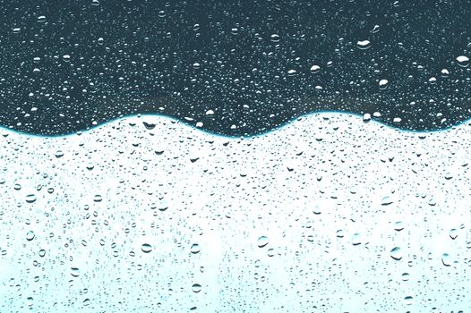 Abstract image capturing raindrops on glass with wavy, reflective surfaces.