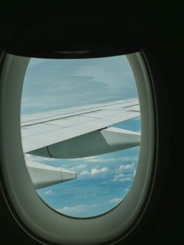 A scenic view of the airplane wing and sky through a cabin window, capturing the essence of air travel.
