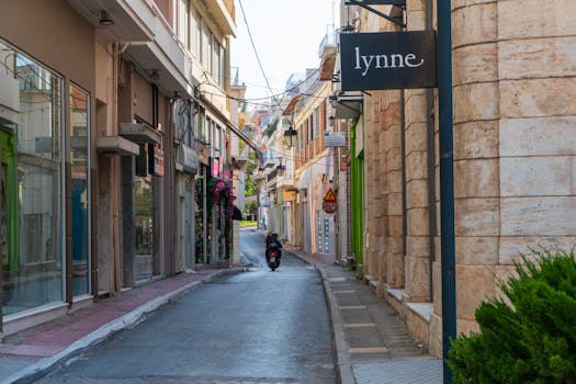 A picturesque narrow street lined with shops and a motorcyclist in an urban setting.