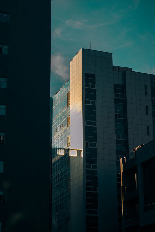 Free A modern office building reflecting light during sunset in an urban city setting. Stock Photo