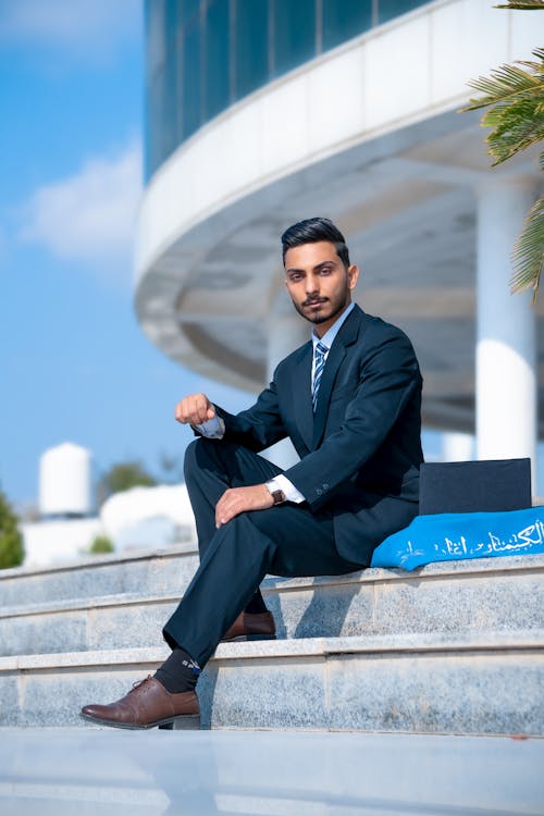 A man in a suit sitting on steps with a laptop