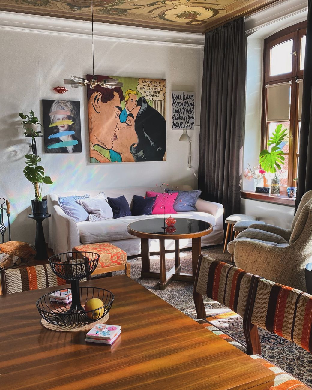 Charming living room with colorful art, vintage furniture, and natural light creating a cozy atmosphere.