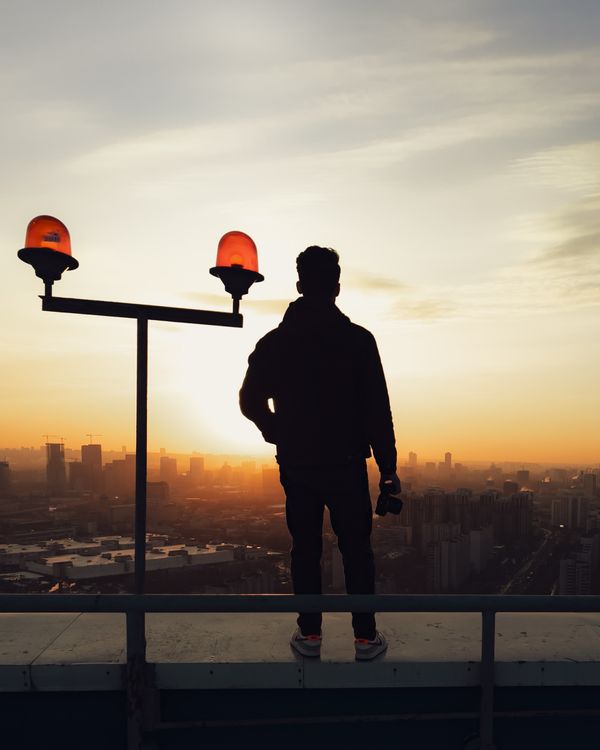 Man Standing on Rooftop at Dusk · Free Stock Photo