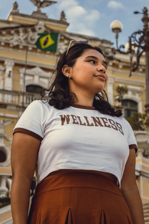 A woman wearing a wellness shirt standing in front of a building