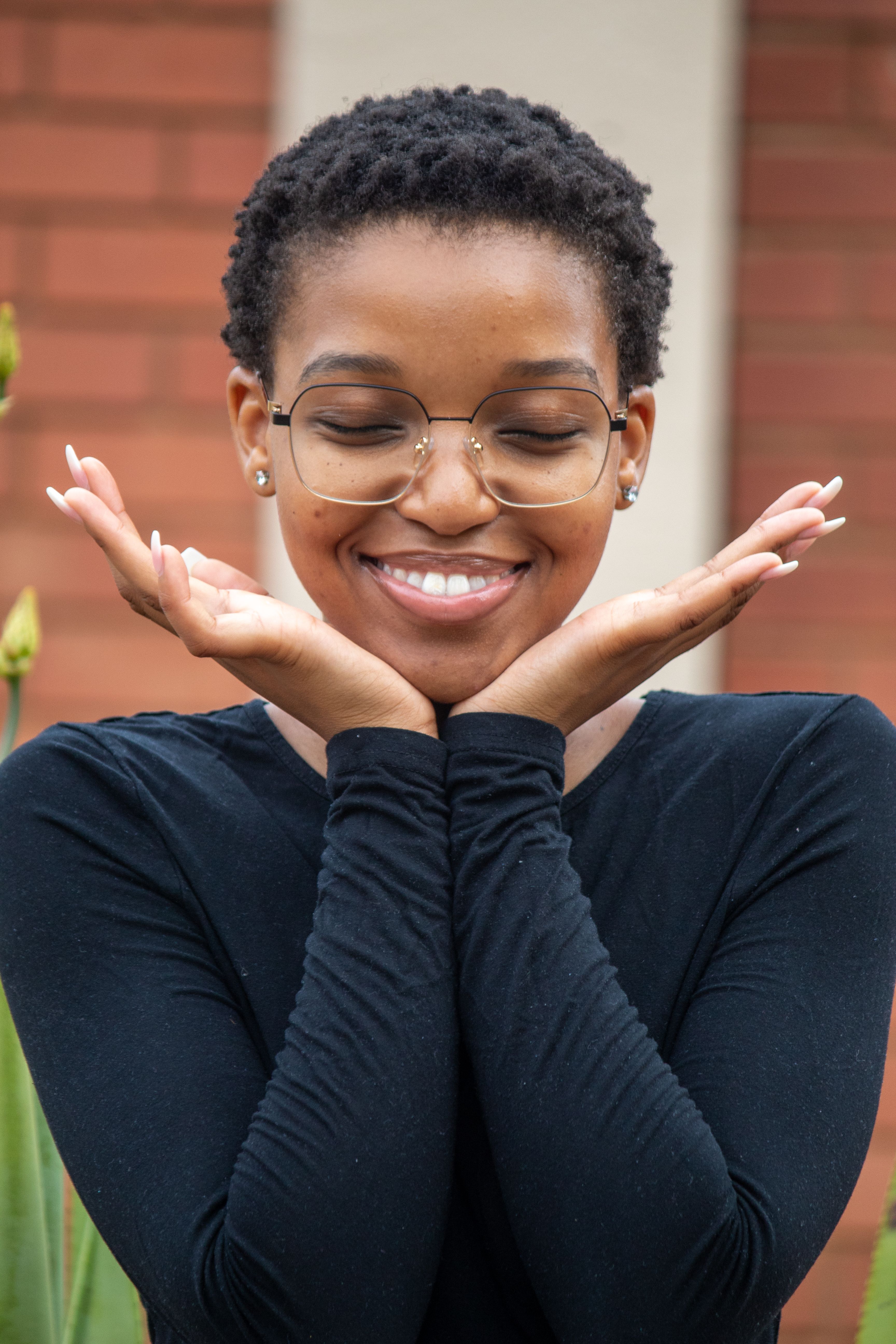 Cheerful woman with eyeglasses smiling with closed eyes, outdoors.