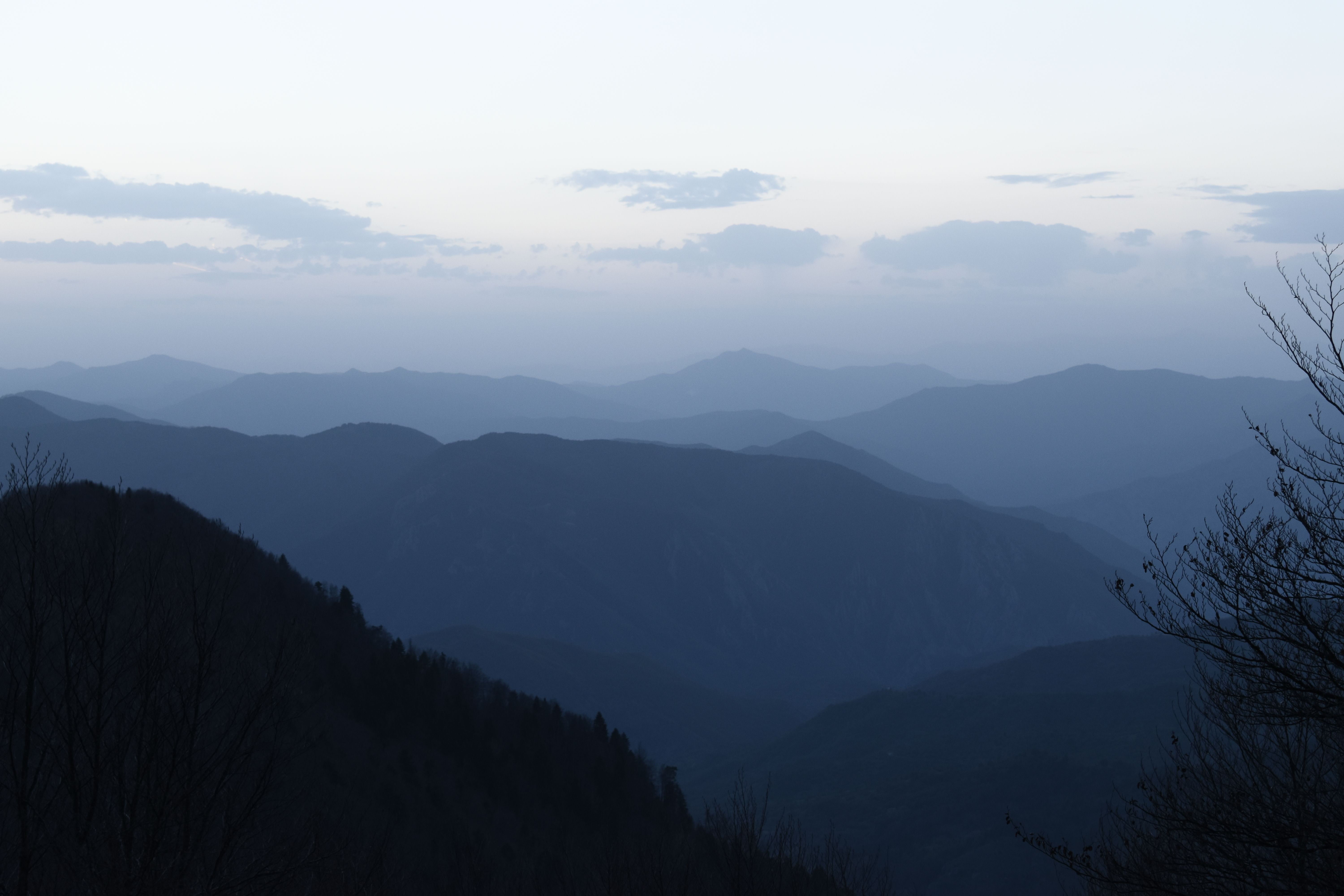 A tranquil mountain landscape at dusk with mist and rolling hills