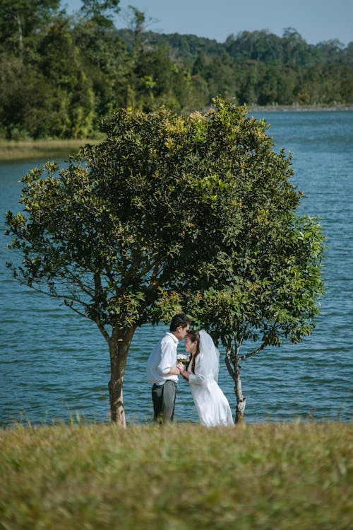 A bride and groom standing by a lake