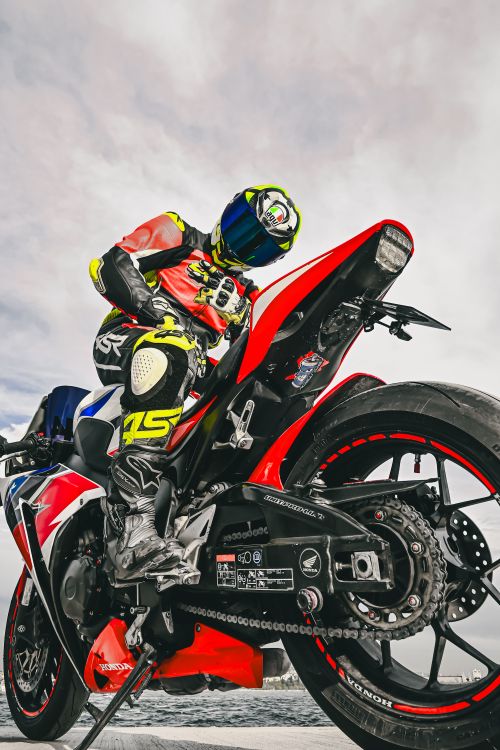 Free Motorcyclist in vibrant gear posing on a red sports bike outdoors. Stock Photo