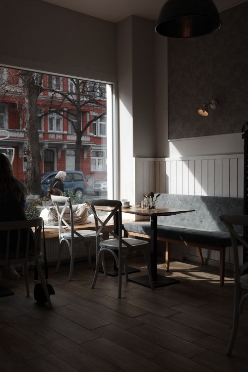 Free Sunlit cafe with wooden floors and window seating in Hanover, Germany, capturing a serene atmosphere. Stock Photo