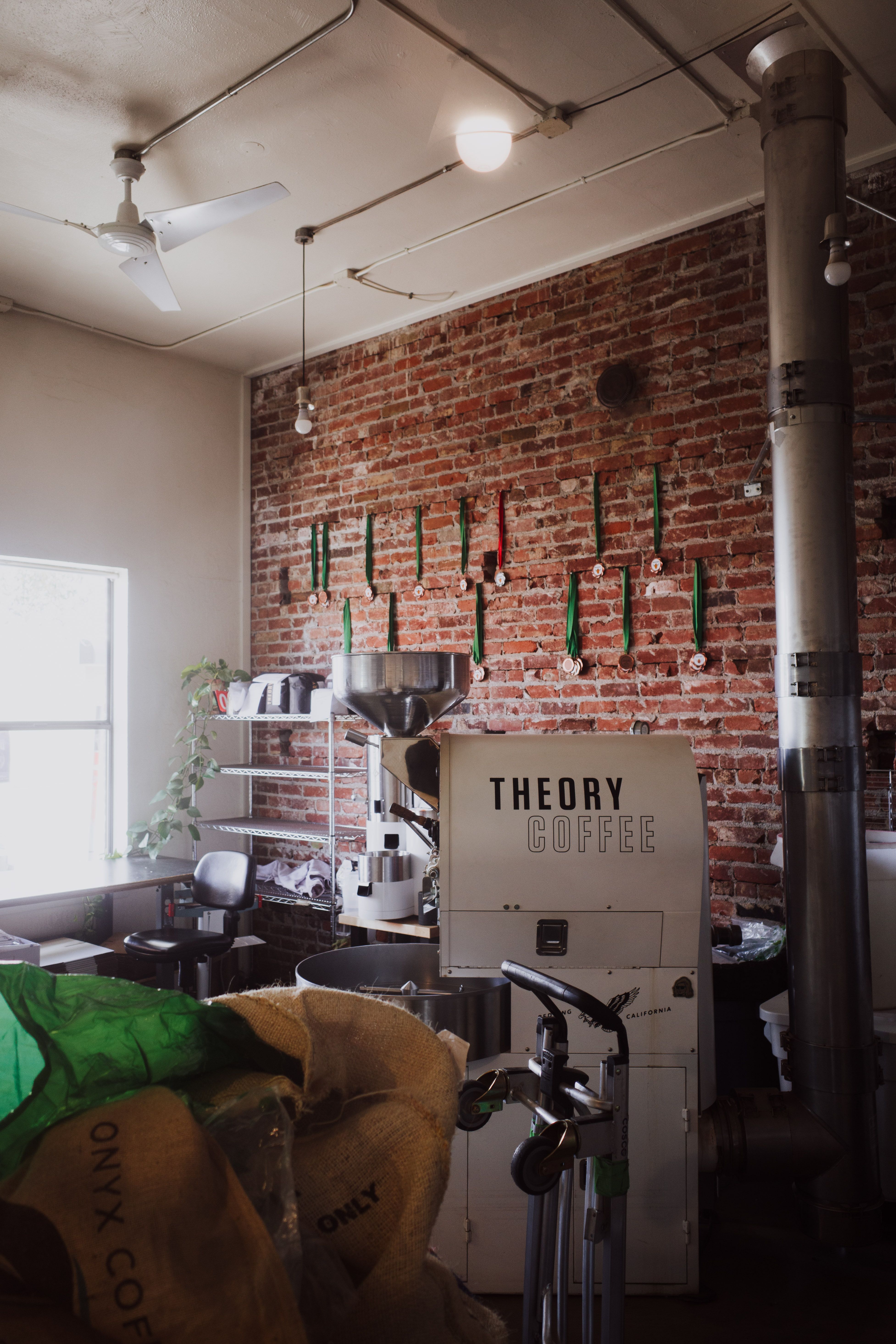 Warm café interior featuring a coffee roaster and rustic brick walls.