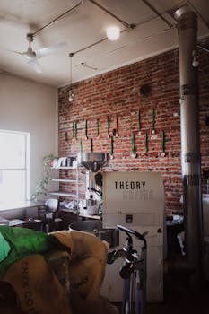 Warm café interior featuring a coffee roaster and rustic brick walls.