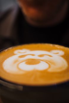 Close-up of a bear-shaped latte art in a coffee cup, showcasing intricate milk foam design.