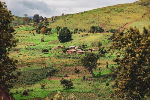 Free A picturesque rural village nestled in rolling green hills, showcasing natural beauty and tranquility. Stock Photo