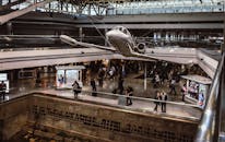 在繁忙的机场里，一架飞机悬挂着，旅客们行色匆匆