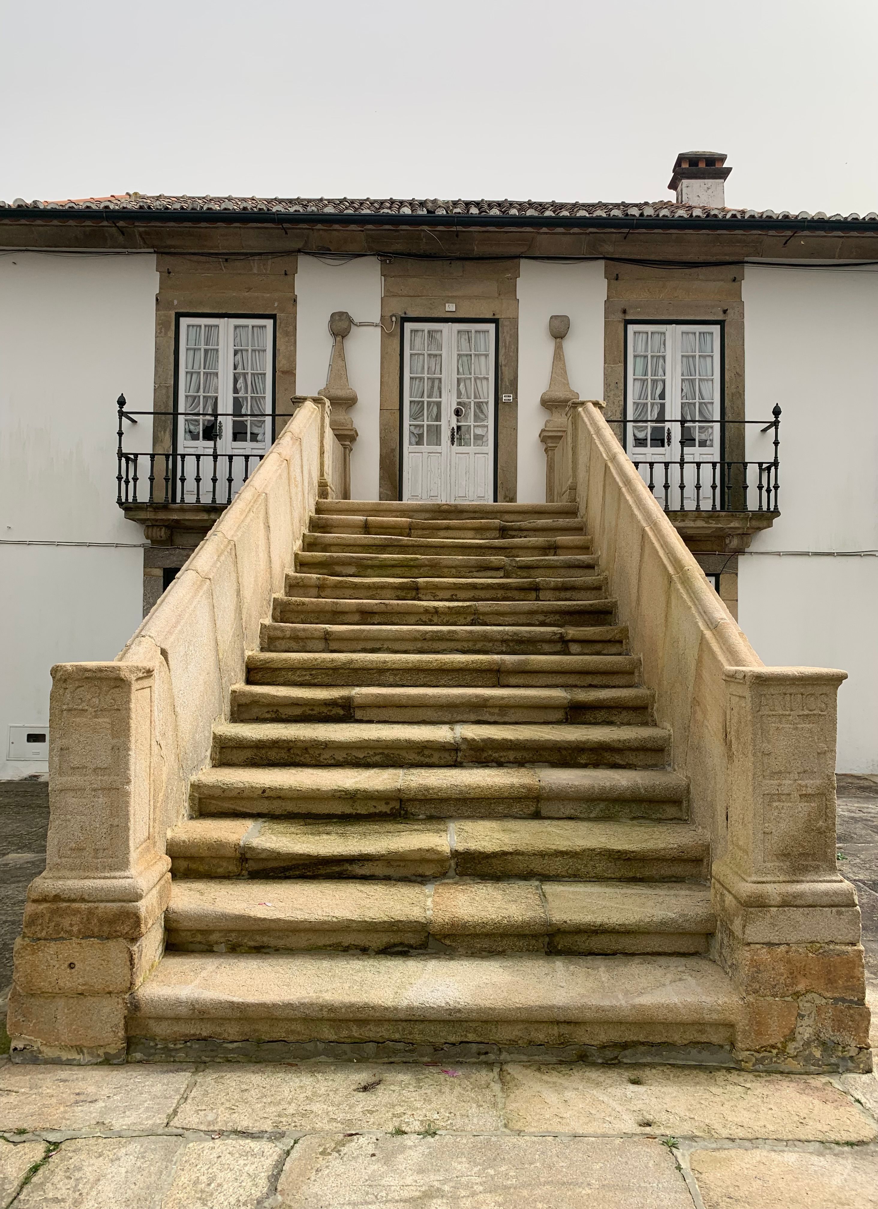Elegant stone staircase leading to a traditional building in Oliveira de Azeméis, Portugal.
