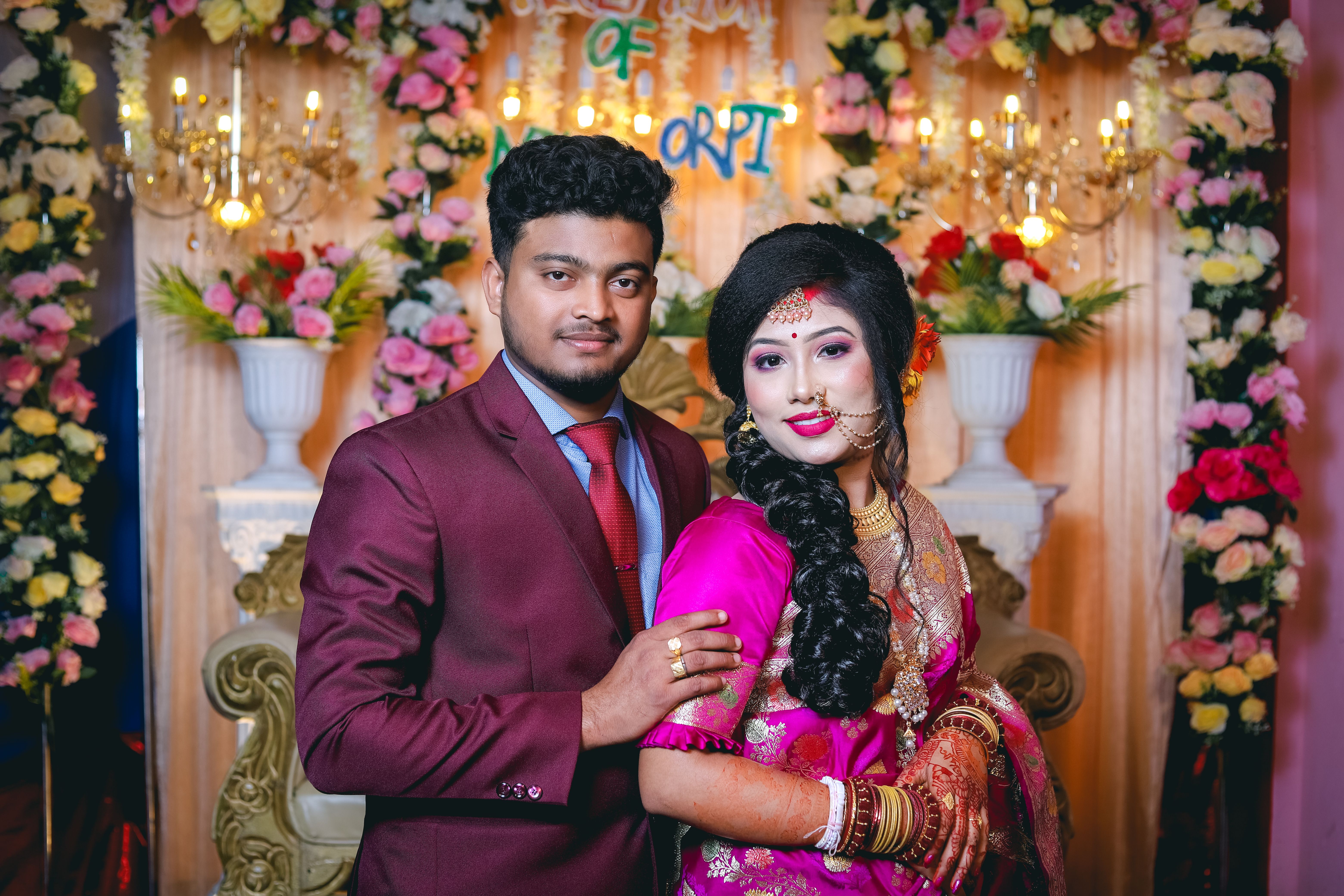 A stunning portrait of a South Asian couple in traditional wedding attire surrounded by floral decor.