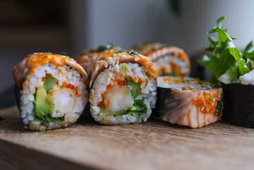 Free Close-up view of sushi rolls with fresh ingredients on a wooden board, showcasing vibrant colors and textures. Stock Photo