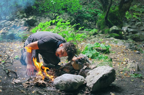 森で焚き火をチェックする男