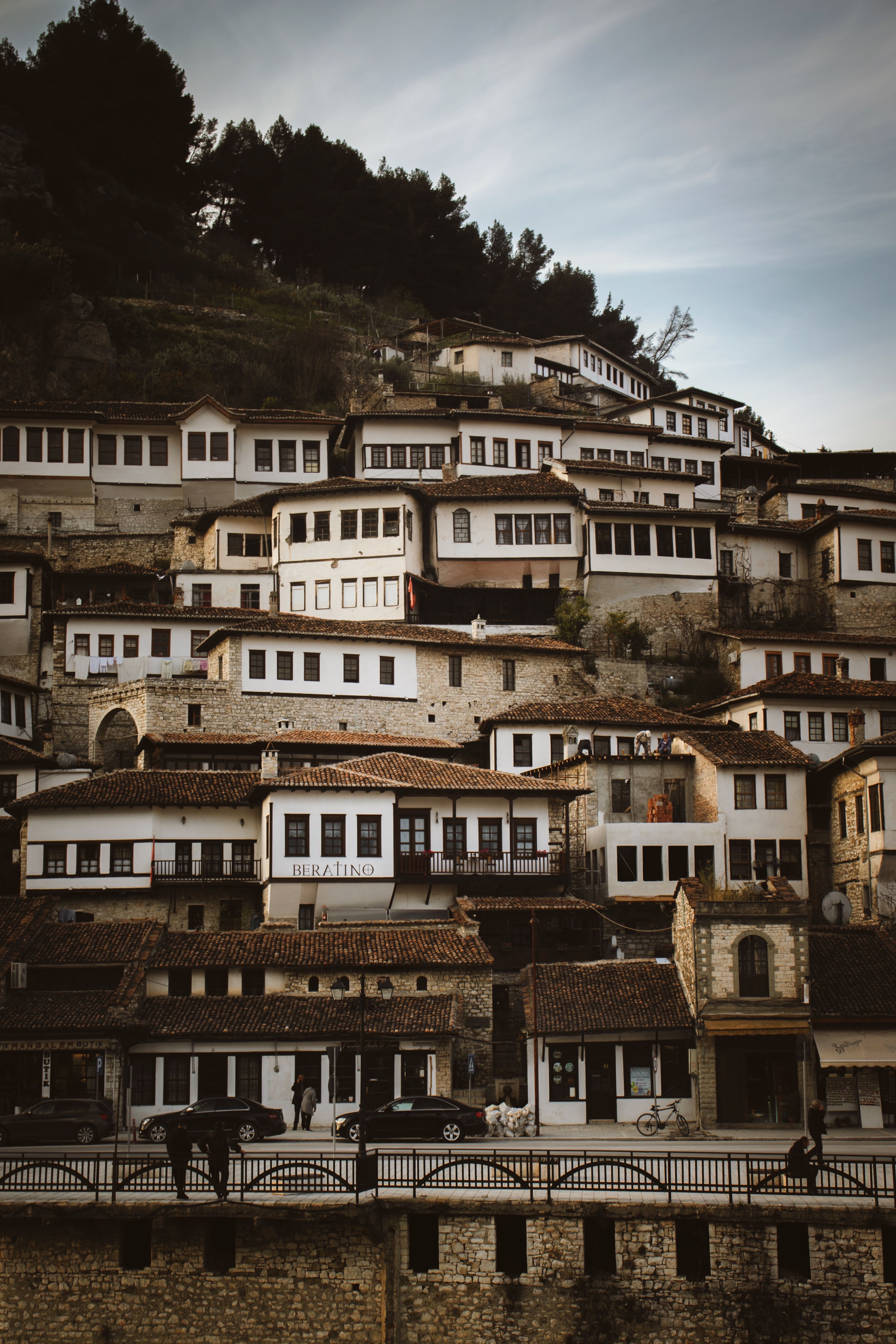 Charming hillside townscape of Berat, showcasing traditional Ottoman architecture in evening light.