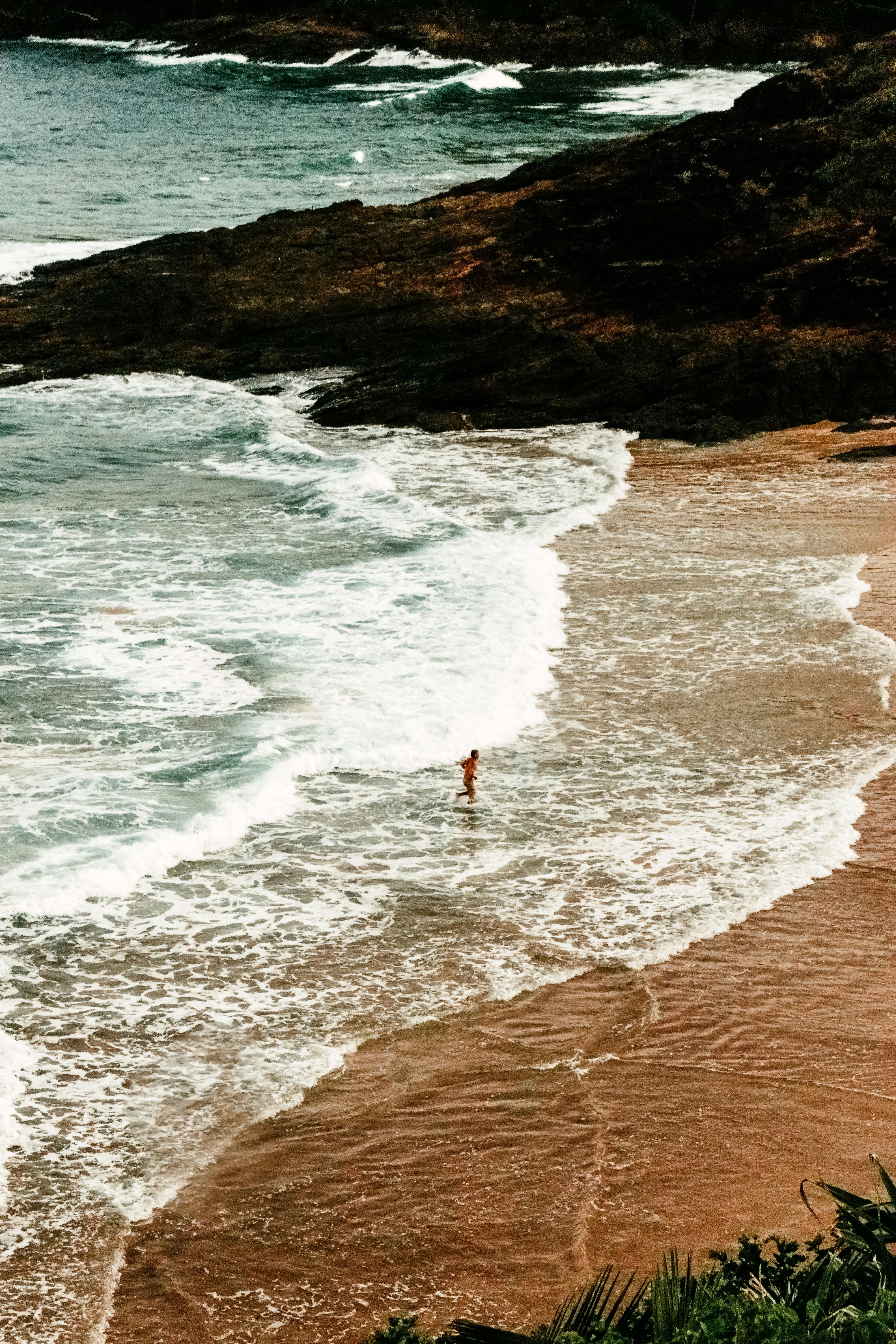 Aerial view of a tropical beach in Itacaré, Brazil with waves and a person enjoying the ocean.