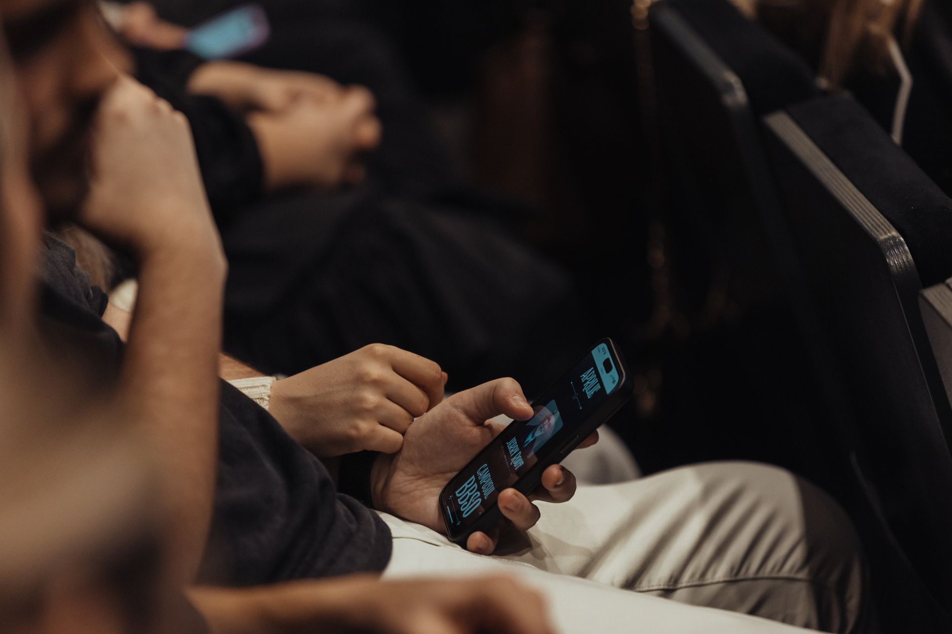 People attending a conference using smartphones, showcasing modern technology engagement.