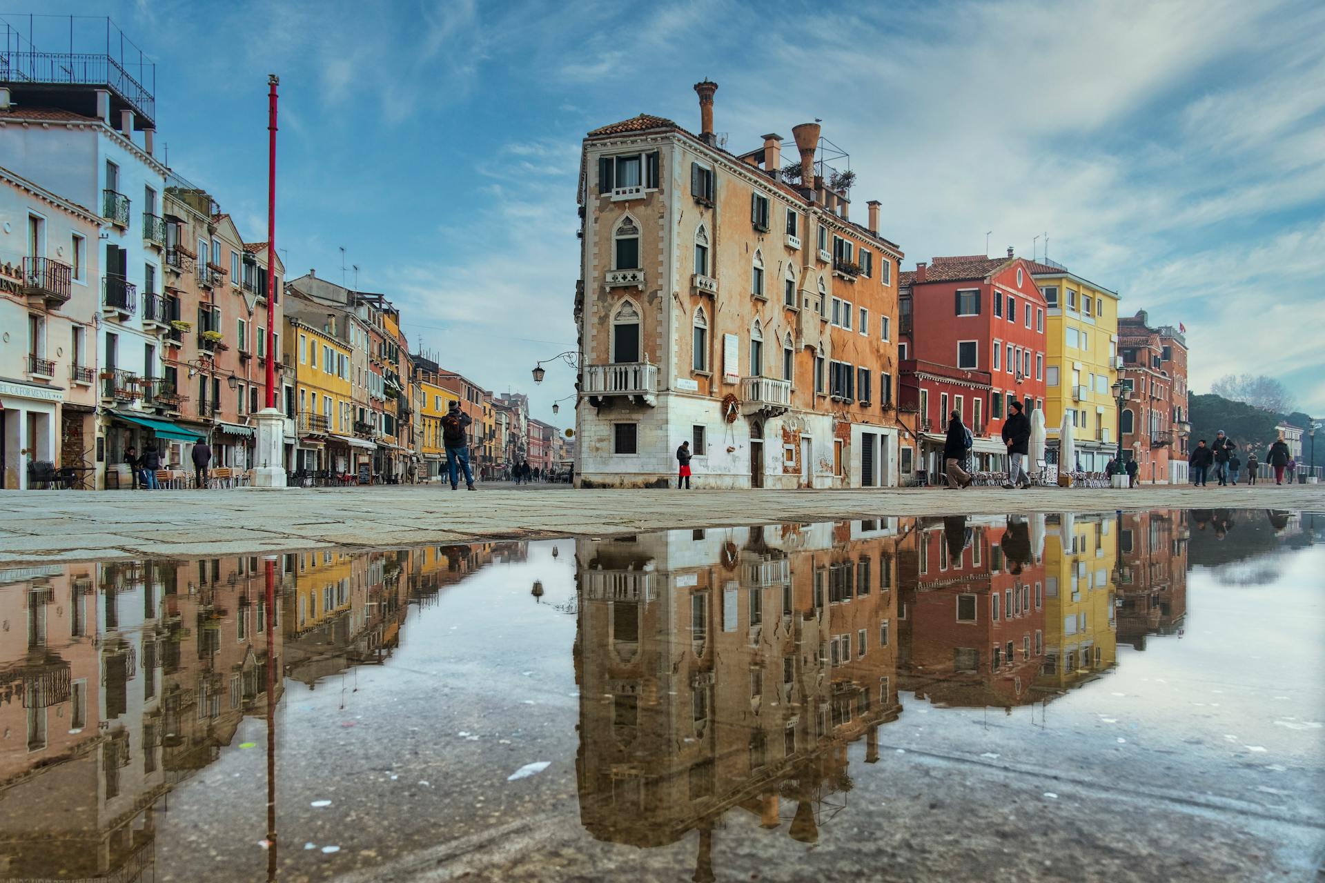 Vibrant colorful buildings reflected in water puddle in Venice, capturing urban beauty.