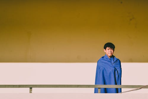 Man Covered With Blue Blanket Standing Near Gray Handrail