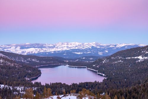 Free Beautiful winter landscape with a snowy mountain range and scenic lake under a pastel sky at sunrise. Stock Photo