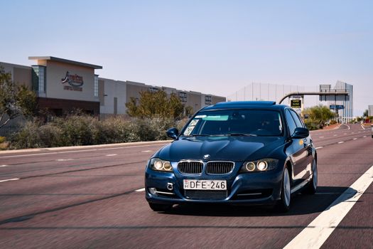 Black BMW car driving down a suburban street, showcasing motion and luxury.