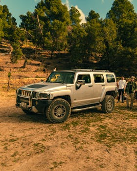 A Hummer H3 parked in a forest clearing, surrounded by people enjoying a summer day.