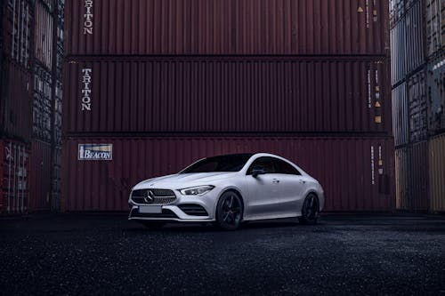The mercedes cla is parked in front of a shipping container