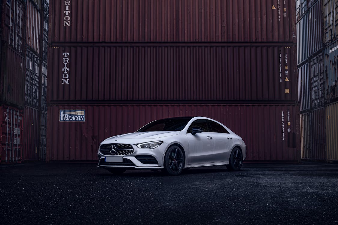 Photo of a Mercedes-Benz CLA Parked next to Containers in a Port 