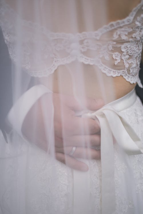 A close up of a bride's hands holding her wedding dress