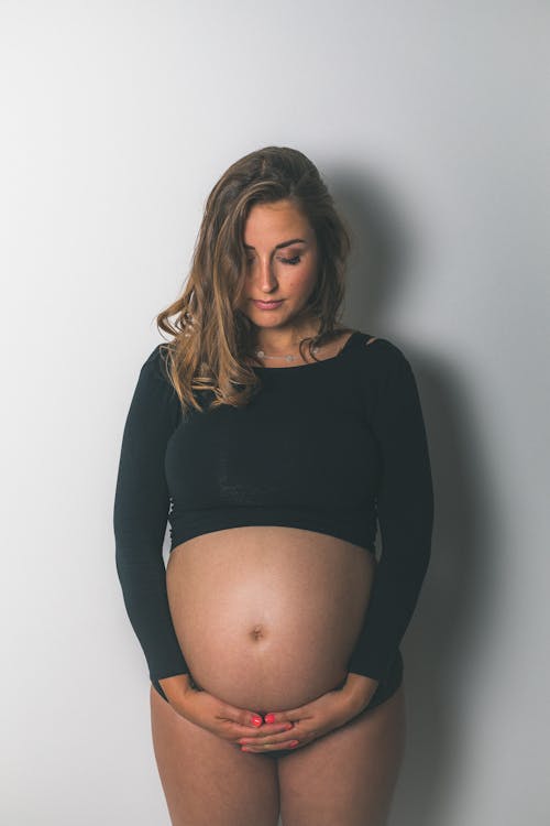 A pregnant woman in black top posing for a photo