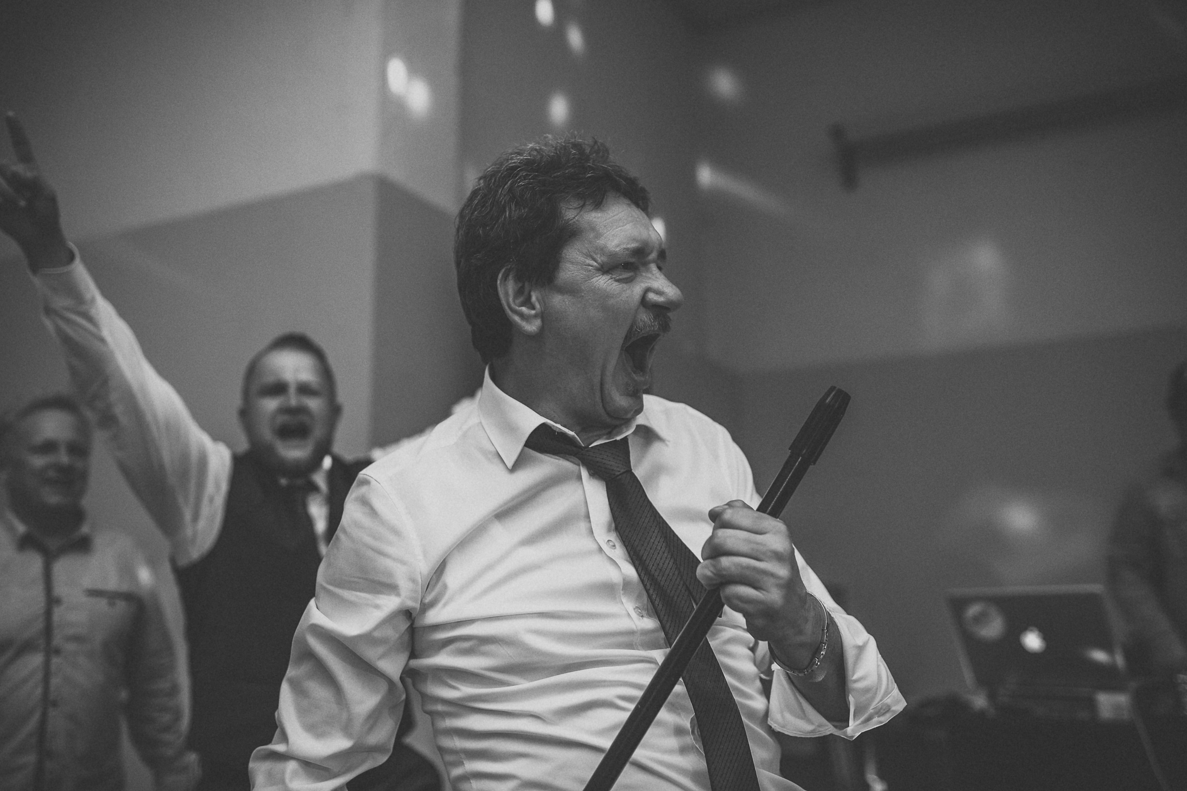 Dynamic grayscale image of men enjoying a lively party atmosphere with laughter and music.