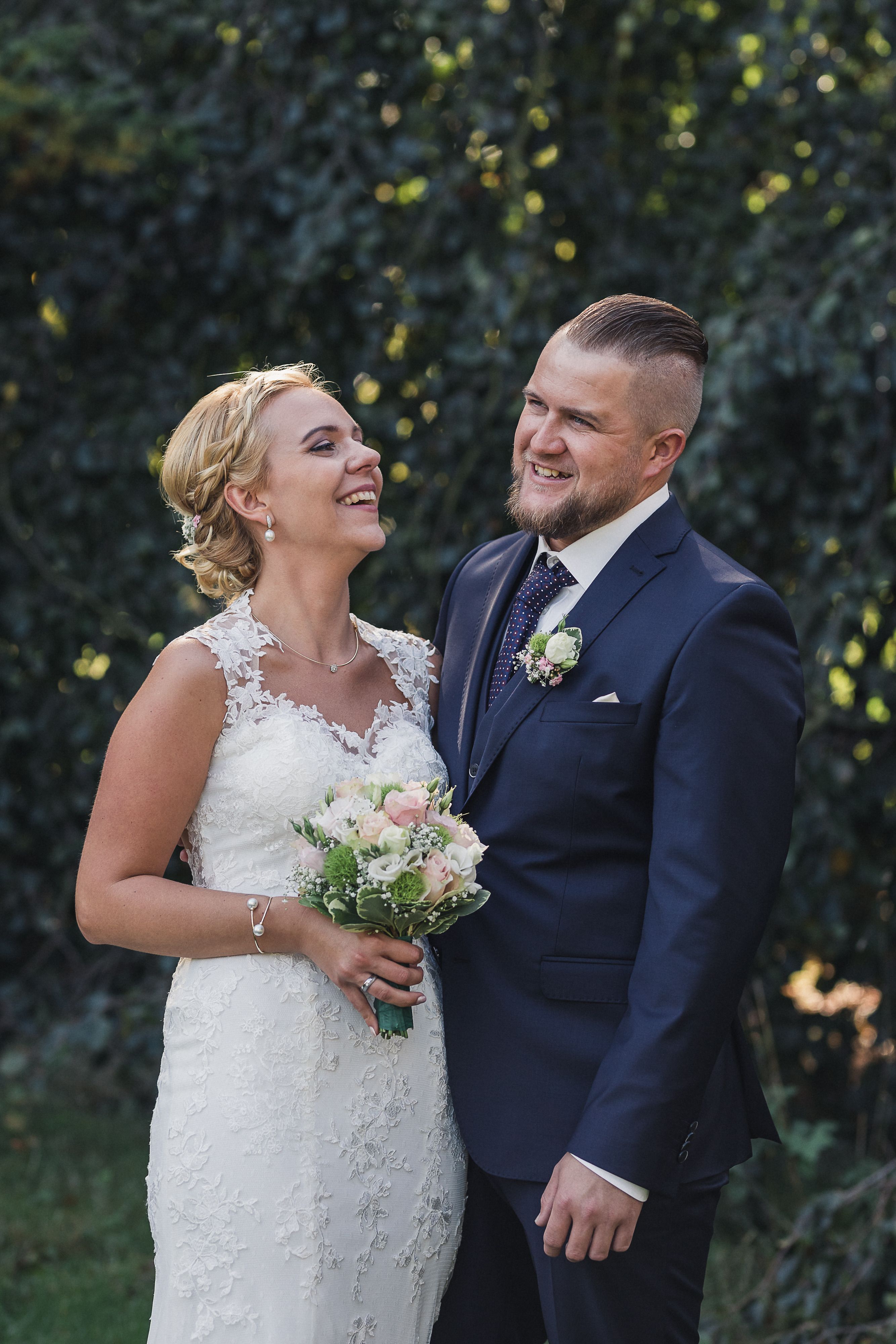 Happy bride and groom smiling in a vibrant outdoor setting.