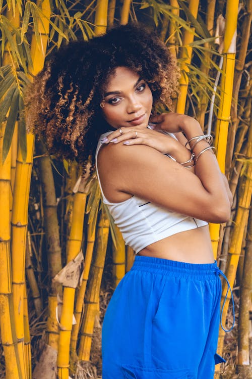 A woman in blue shorts posing in front of bamboo trees