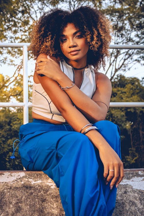 A woman with curly hair sitting on a ledge