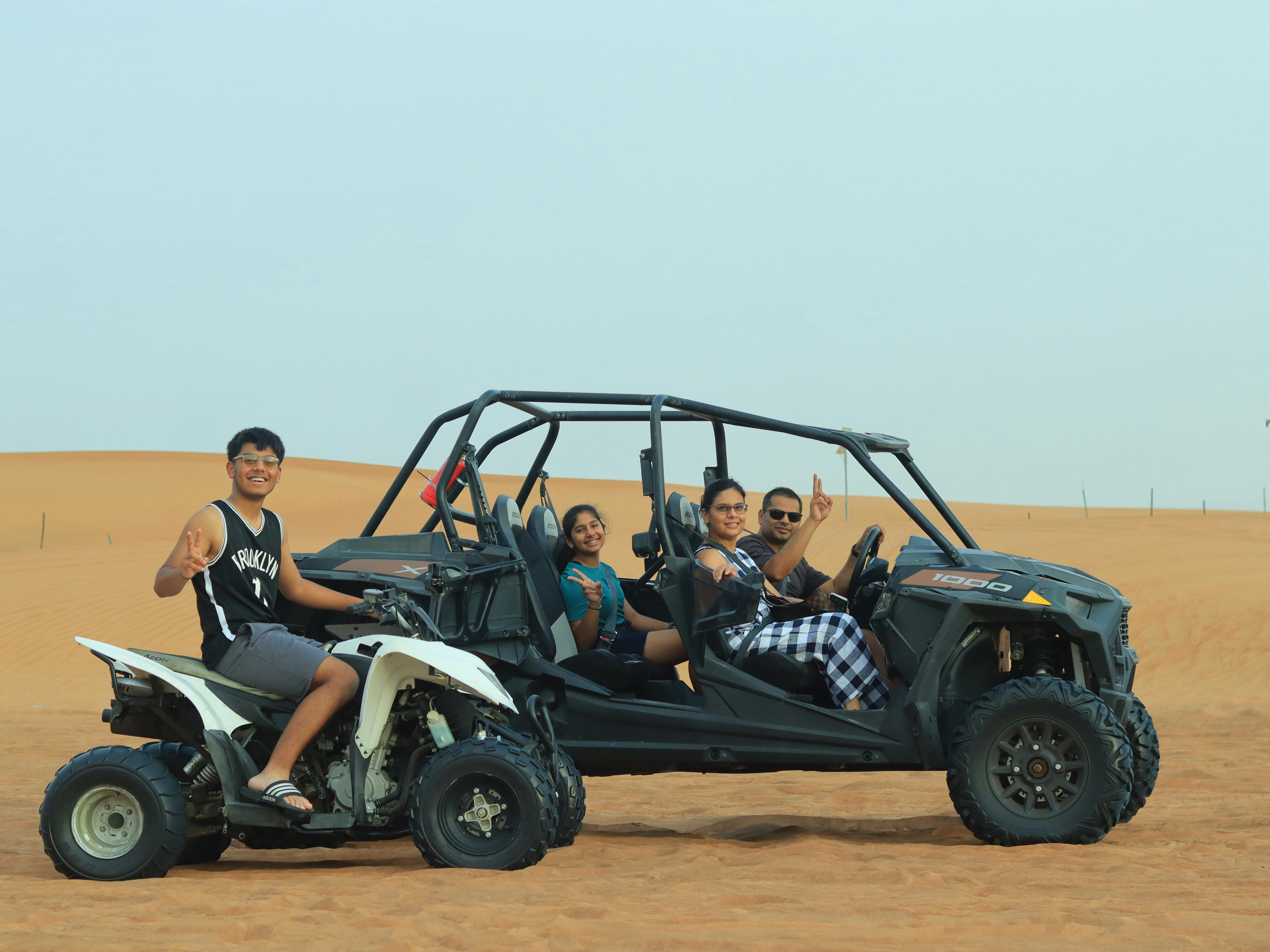 Family enjoying an ATV adventure in the Dubai desert, posing for a fun vacation photo.